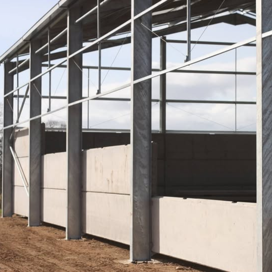 Concrete wall panes situated on the side of a steel-framed agricultural building. 